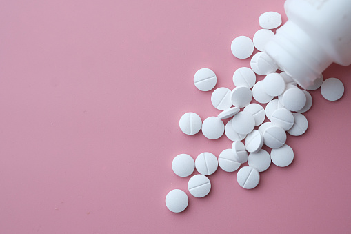 white pills spilling on pink background, Top view .