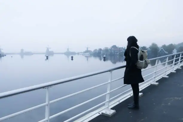 Photo of Young asian woman standing in fence with view of the windmill