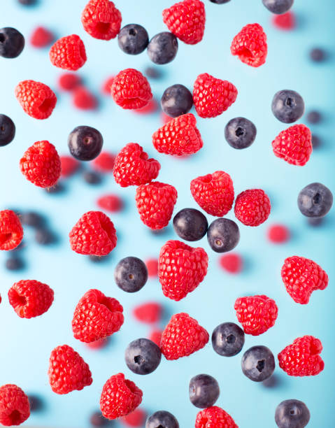 istock Flying berries on a blue background. Falling raspberry and blueberries fruits 1225809049