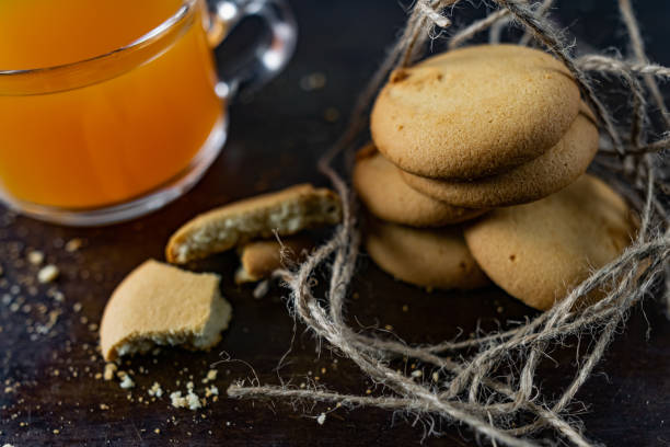 istock Homemade shortbread, round-shaped pastry on a dark old surface in a stack of crumbs. Next to it is a glass mug with 1225809405