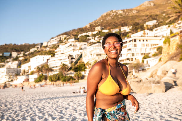 Portrait of a smiling African woman Portrait of a confident African woman at the beach. She is looking at camera black woman bathing suit stock pictures, royalty-free photos & images