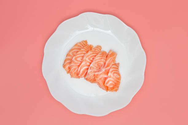 salmon on a dish on pink background.
