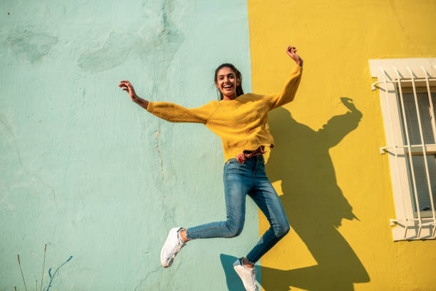 Jump! Young Indian woman jumping.She has light blue wall as a background excited woman yellow stock pictures, royalty-free photos & images