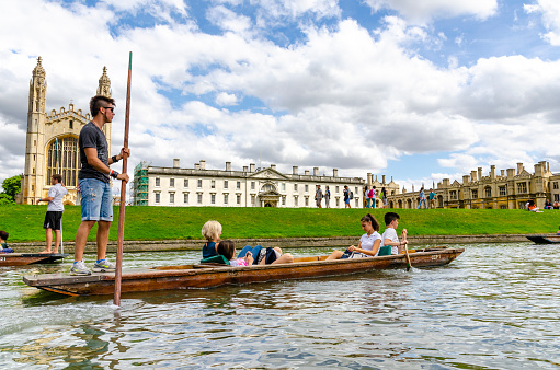Cambridge, UK - June 6th, 2018; Punting on the river Cam through the colleges and universities of Cambridge city, UK is a huge tourist attraction for both young and old alike and a source of income for students who act as both punters and tour guides.