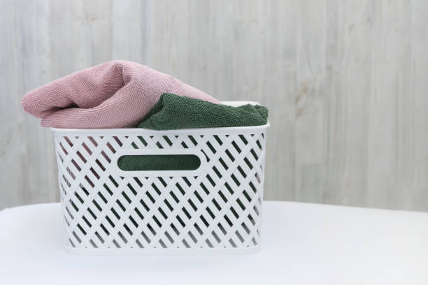 istock White plastic basket with clean multi-colored towels on a wall background. Copy spase 1225822314