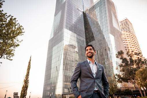 Portrait of a handsome smiling businessman outside his office in the sunset