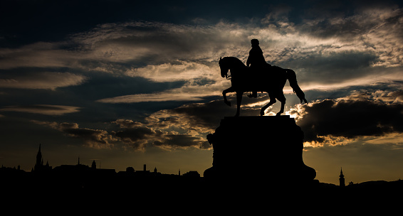 A picture of the Gyula Andrássy statue against the sunset, in Budapest.