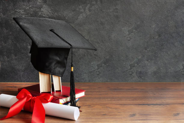 istock Academic cap and graduation diploma scroll and tied with red ribbon. 1225825136