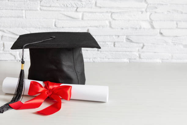 istock Academic cap and graduation diploma scroll and tied with red ribbon. 1225825162