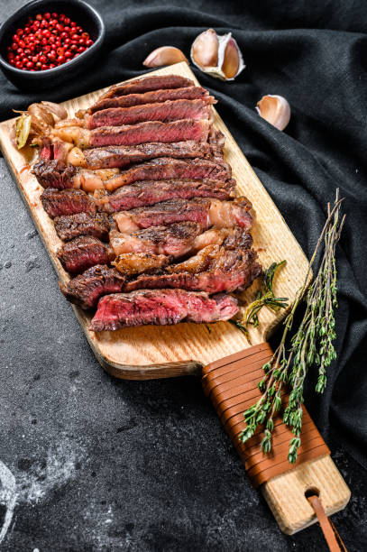 istock Grilled rib eye, ribeye steak on a chopping Board, medium rare. marbled meat. black background. top view 1225825604