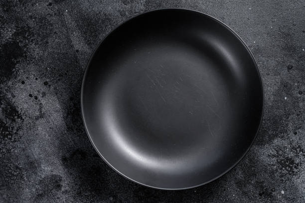 istock Black plate on textured black background.  Top view. Copy space 1225826286