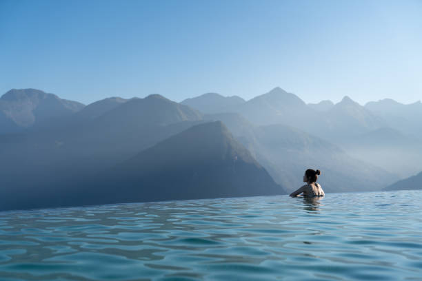 donna sexy rilassante in piscina a sfioro guardando una splendida vista sulle montagne nel lussuoso resort / concetto di vacanza - infinity pool foto e immagini stock