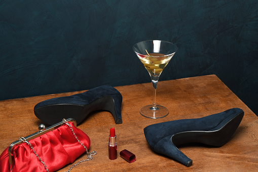 Female accessories with glass of cocktail on wooden table