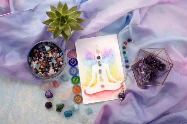Natural crystals and pendulum on pastel silk background. Reiki background with card. Top view
