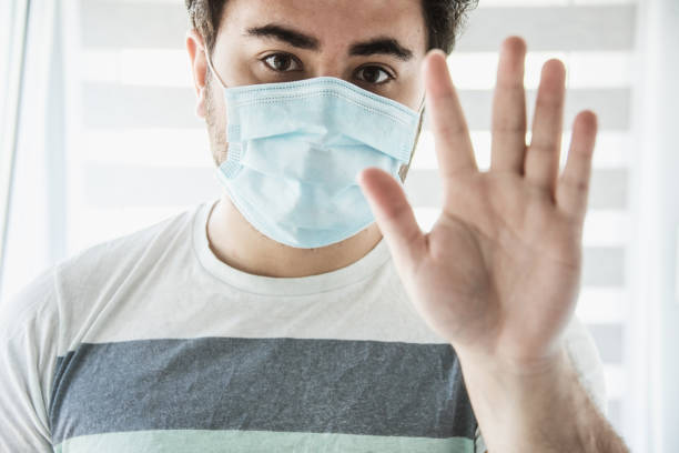 istock Young man with protective fce mask waving 1225827131