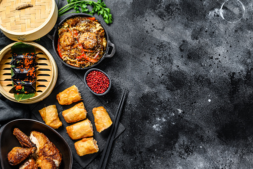 Chinese food. Noodles, dumplings, stir fry chicken, dim sum, spring rolls. Chinese cuisine set.  Black background. Top view. Copy space.