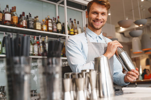 istock Cheerful bartender in apron mixing cocktail with shaker 1225828155