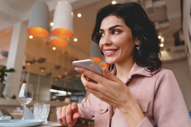 istock Joyful young woman talking on mobile phone in cafe 1225828340