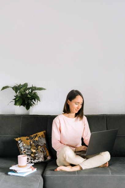 istock Young woman sitting on the couch and using laptop. 1225829398