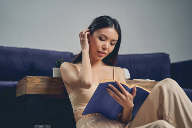 istock Charming young woman reading book at home 1225830015