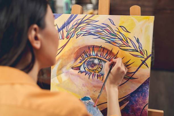 young woman painting eye on easel in home art studio - artist art artists canvas human eye imagens e fotografias de stock