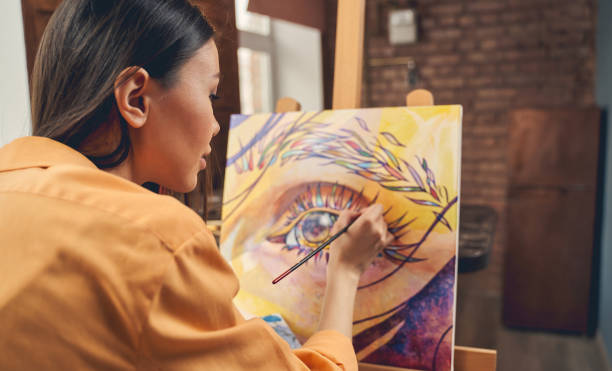beautiful young woman painting eye on easel at home - artist art artists canvas human eye imagens e fotografias de stock