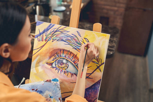 young woman painting beautiful picture on easel at home - artist art artists canvas human eye imagens e fotografias de stock