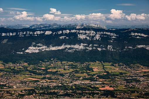 Misty rolling landscape with some mountain peaks early in the morning, close-up on Mont Revard near the French city of Aix les Bains. This photo was taken in middle of summer from the top of La Dent Du Chat mountain peak in end of Bugey mountains, European Alps in border of Ain and Savoie department, in Auvergne-Rhone-Alpes region in France, Europe.