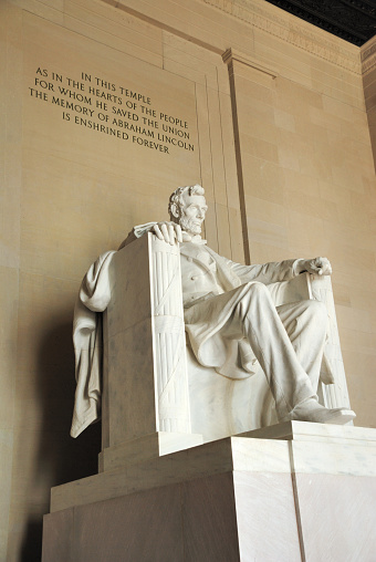 Abraham Lincoln statue in Lincoln Memorial in Washington DC, with famous quote inscribed on wall above.