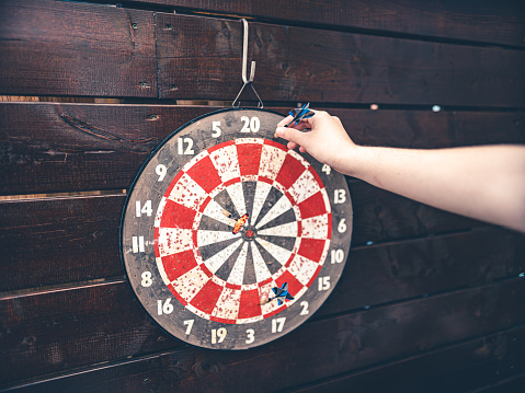 Hand of Teenage boy enjoying his hobby: He is  in outdoors on the patio, practising darts