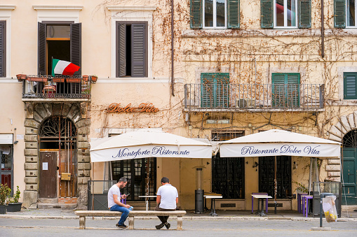 Rome, Italy, May 18 -- Some persons take a break in front of a restaurant closed in the famous Piazza Navona still empty and without tourists despite the end of the restrictions imposed by the lockdown for the Covid-19 crisis and the general reopening.