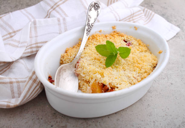 Crumble with strawberries and apples on a white plate and concrete background.