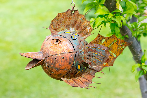 rusty metal fish weighs on a tree. Pendant decoration. Sale of souvenirs. Funny handmade fish