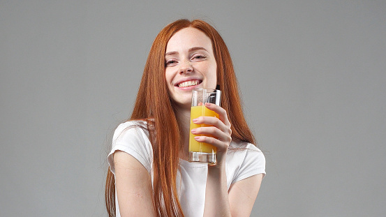 Beautiful young woman happy and drinking orange juice. young woman holding glass of orange juice.