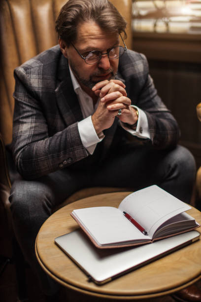 istock Mid-age businessman sits at table and thinks over his notes in notepad in office 1225846270