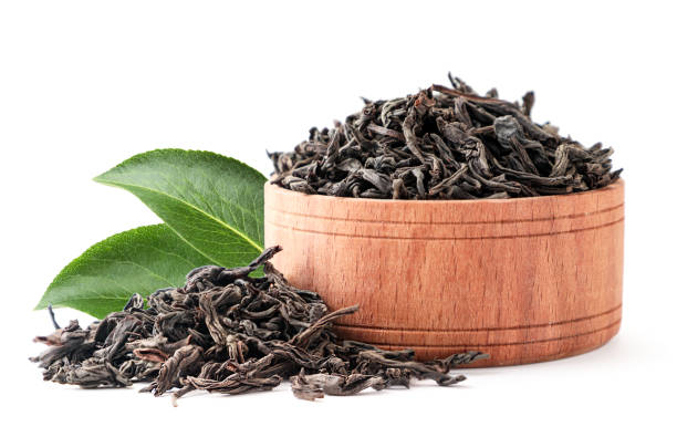 istock Black tea in a wooden plate with a green leaf on a white background. Isolated 1225846689