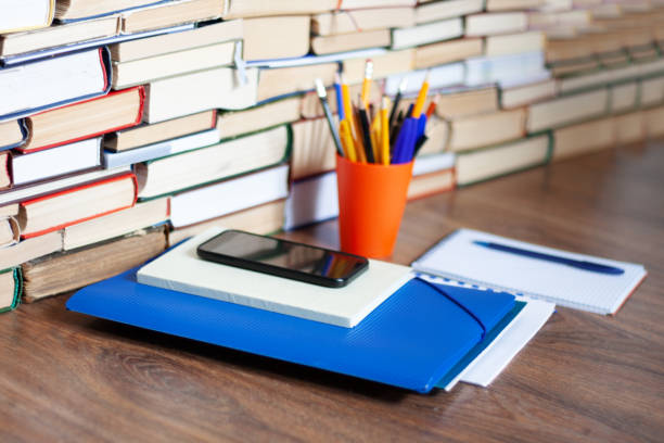 istock Textbook, notebook, mobile phone smartphone, stack of books. Home distance education background, stay home concept 1225846721