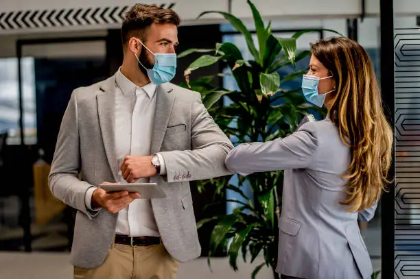 Photo of Business people greeting during COVID-19 pandemic, elbow bump