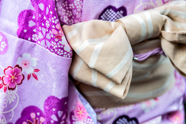 kioto, japón primer plano de la mujer en kimono púrpura con patrón rosa primavera flor de cerezo y cinturón obi de arco atado - obi sash fotografías e imágenes de stock