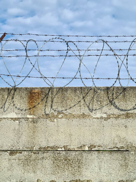 istock Barbed wire on concrete fence 1225852361