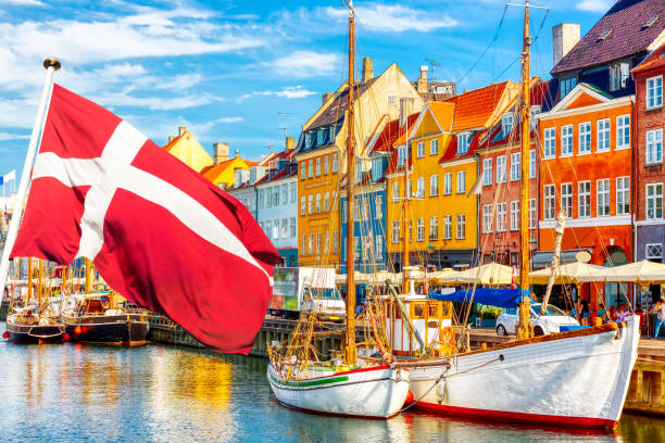 vista icônica de copenhague. famoso porto de nyhavn no centro de copenhague, dinamarca durante o dia ensolarado de verão com bandeira dinamarquesa em primeiro plano. - cloud house blue danish culture - fotografias e filmes do acervo