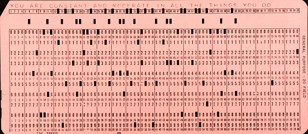 Artifact of obsolete technology. Close-up of computer punch card used in the 1950s and 1960s with room-sized computers. Each has a message at the top--sort of like old technology fortunes. This one says, \