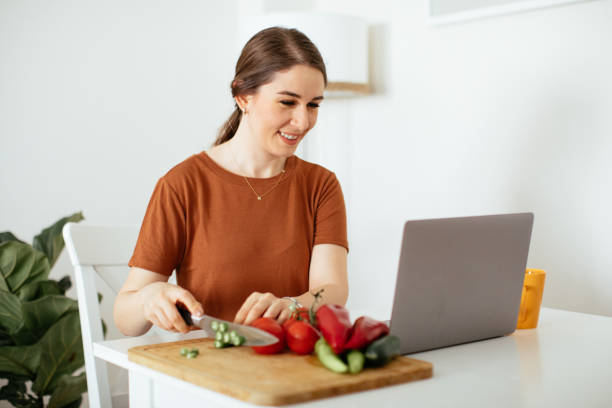 istock Young woman preparing food while working from home 1225855408