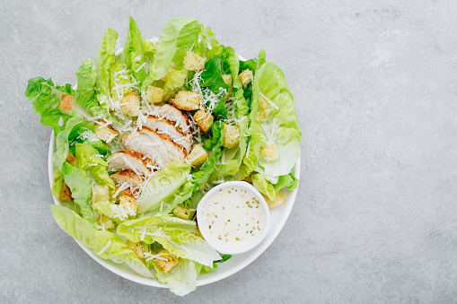 Traditional Caesar salad with chicken, romaine lettuce, croutons and parmesan cheese. Top view, copy space.