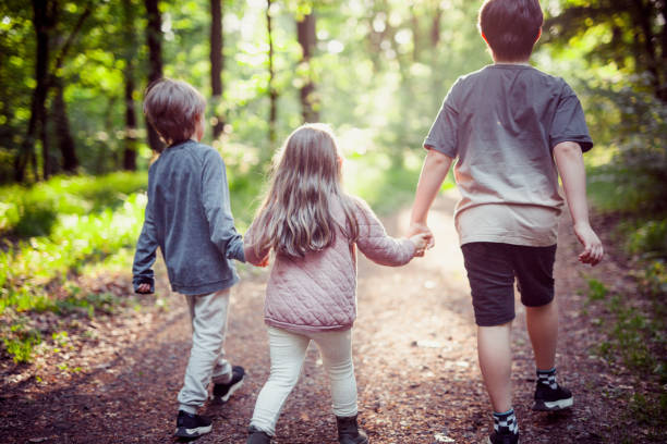istock Schoolchildren are holding hands. They are walking in the forest. 1225856435