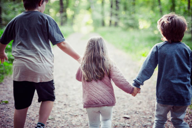istock Schoolchildren are holding hands. They are walking in the forest. 1225856437