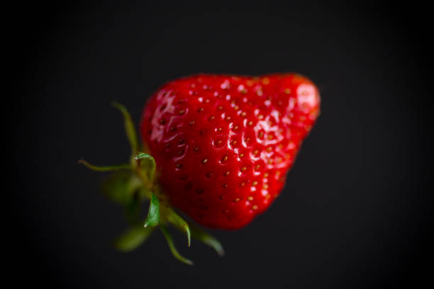 one red ripe strawberry isolated on a black background