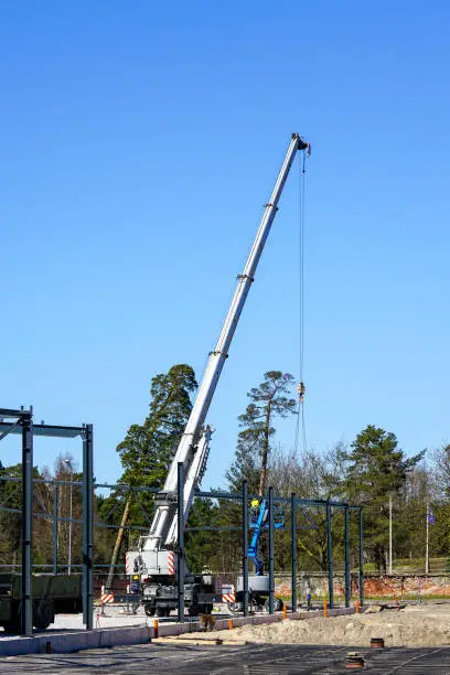 Photo of Truck mounted crane with a telescoping boom at constructing a metal carcas of a new building