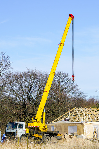Truck mounted mobile crane with a telescoping boom at constructing a carcas of a new wooden building