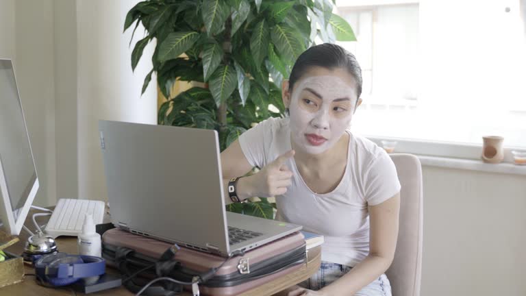 Woman applying beauty face cream, while online chatting at home